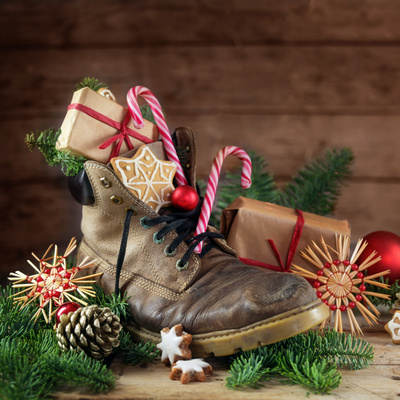 KI generiert: Ein Stiefel gefüllt mit Geschenken, Lebkuchen, Zuckerstangen und Tannenzweigen.